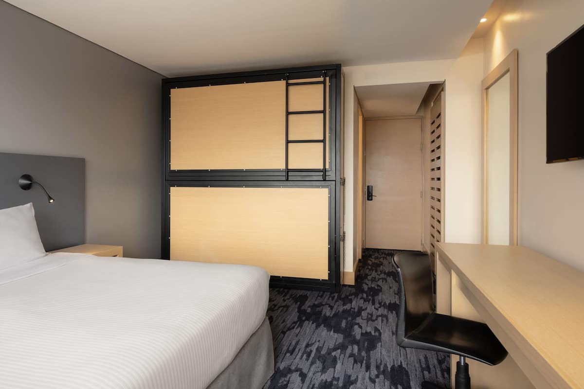 A hotel room with a bed, a desk, and a walk-in closet.