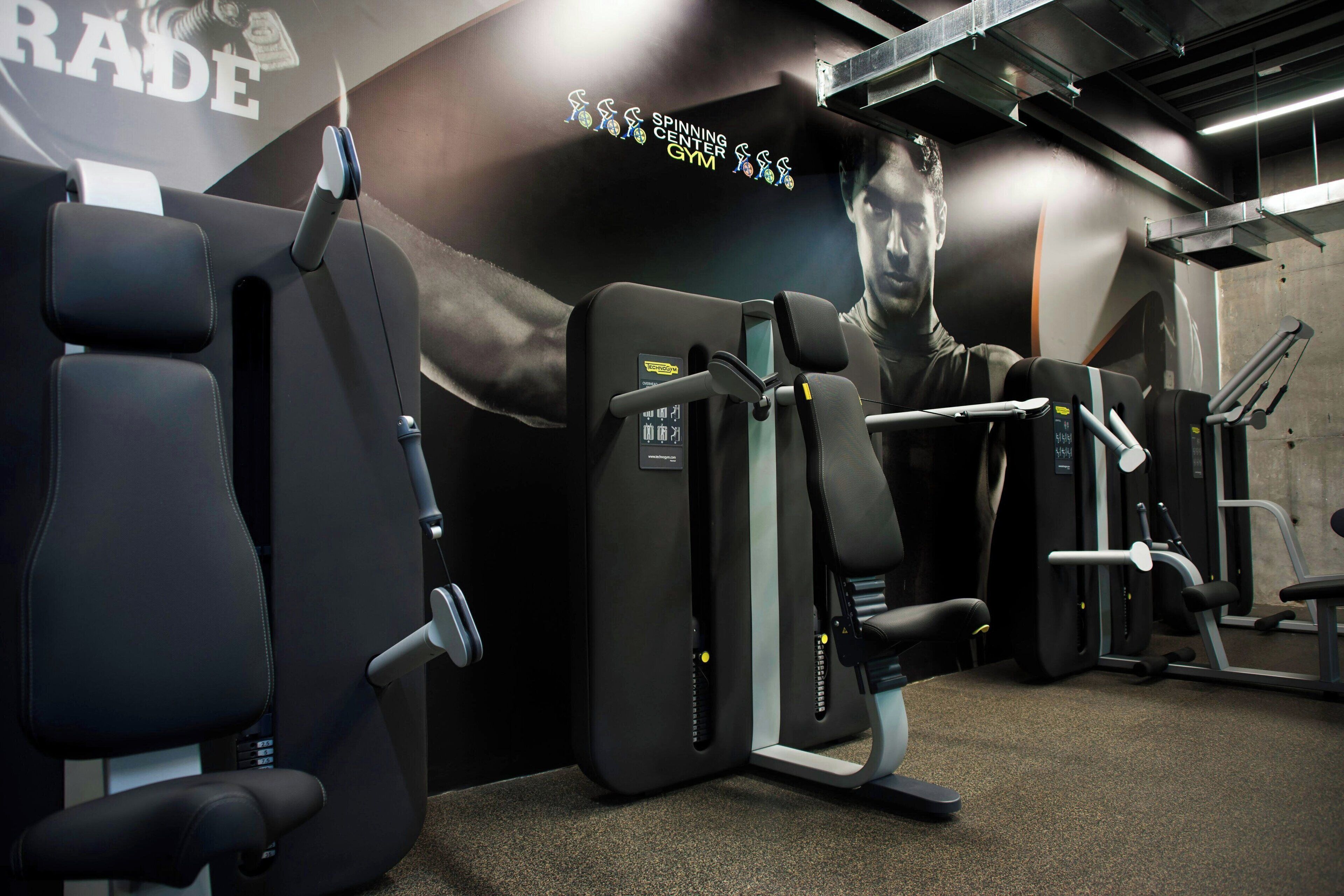 A gym with exercise equipment and a large mural on the wall.