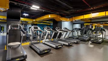 A gym with multiple treadmills, exercise equipment, and a motivational wall with the text "COME BEAT YOURSELF".