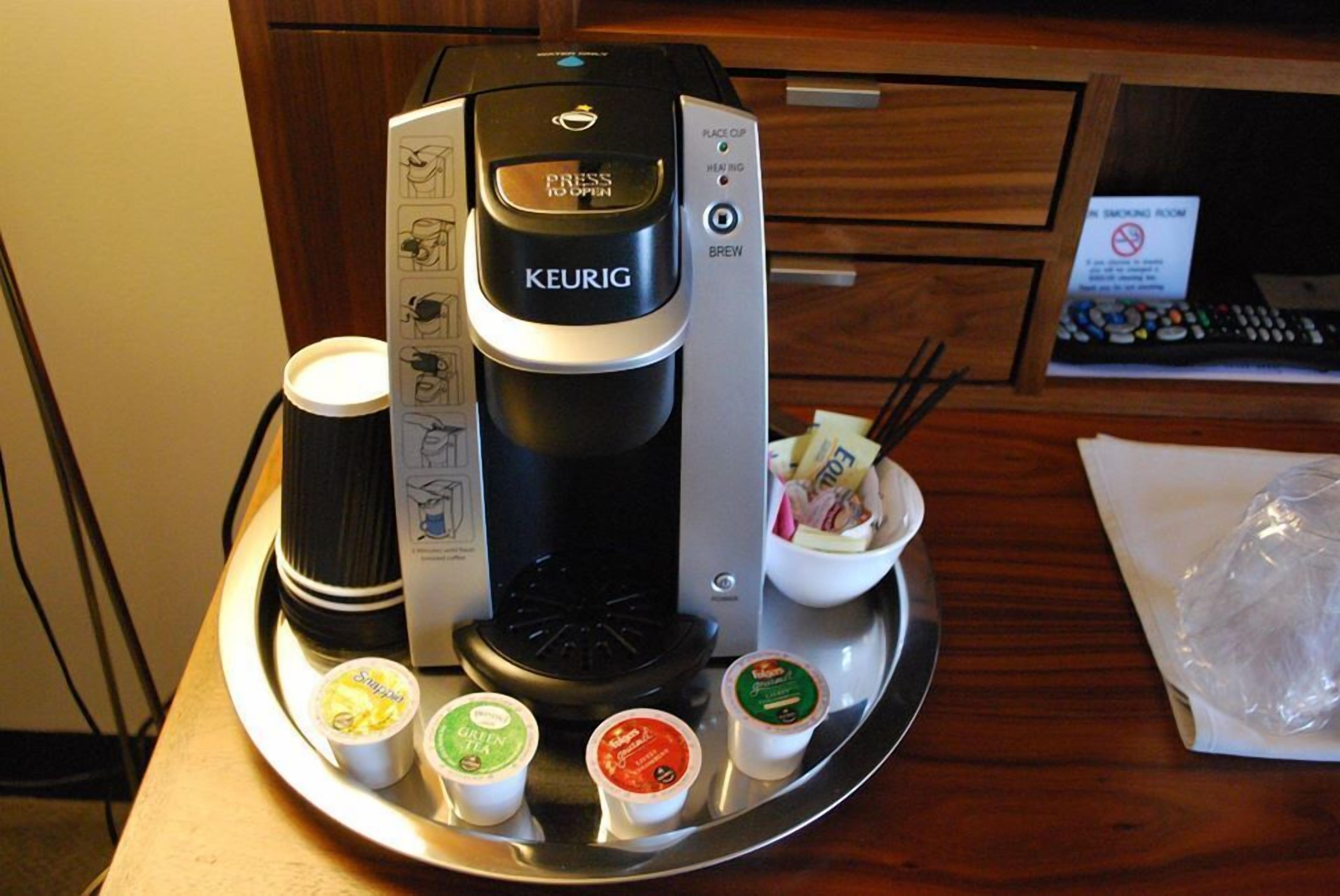 A Keurig coffee machine with a tray of coffee pods and a cup.