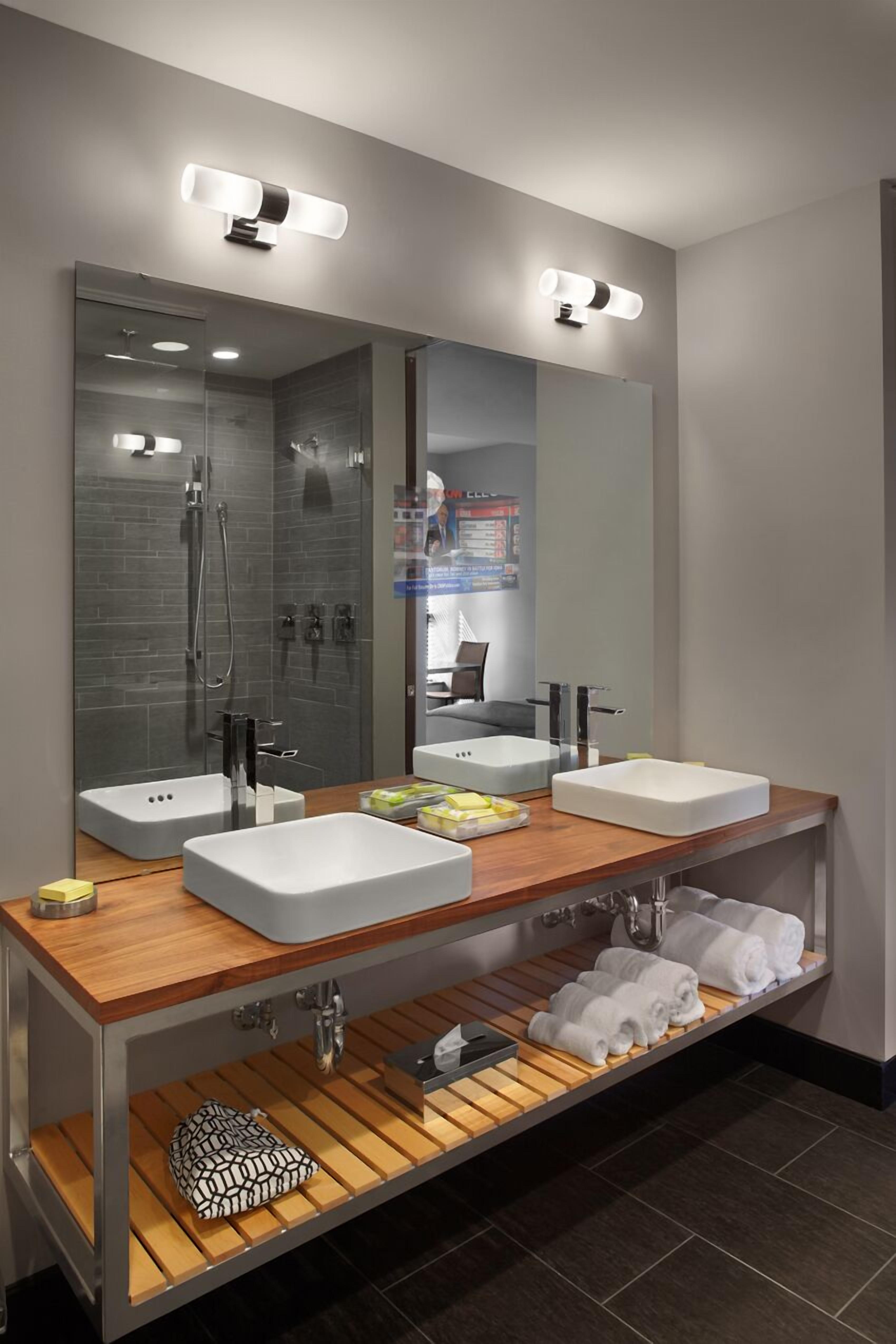 A modern bathroom with two sinks, a shower, and a large mirror.