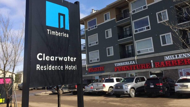 A sign for Timberlea's Clearwater Residence Hotel with a modern building in the background. - Clearwater Residence Hotel Timberlea (Fort McMurray)