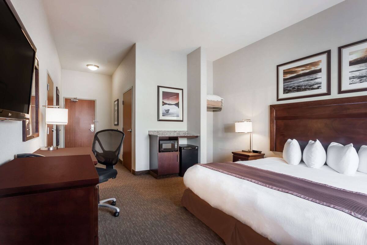 Una habitación de hotel con cama, escritorio, silla, microondas y televisión.