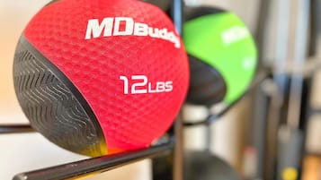 Banco de pesas con discos rojos y verdes etiquetados como "MD Buddy 12 LBS".