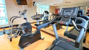 Un gimnasio con cintas de correr y bicicletas estáticas, un espejo grande y una frase motivadora en la pared.