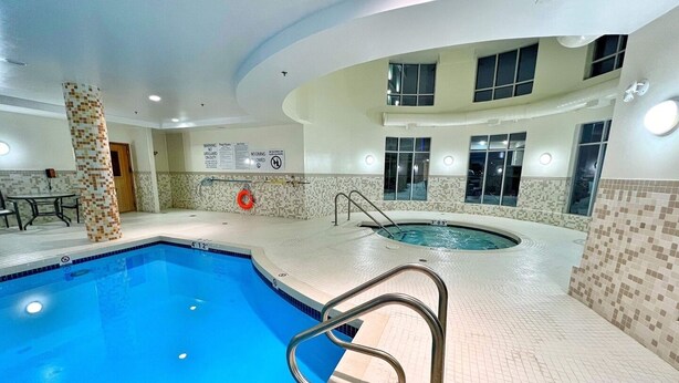 Una piscina interior con trampolín, paredes de azulejos y un puesto de socorristas.