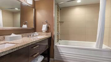 A bathroom with two sinks, a large mirror, a bathtub, and a shower curtain.