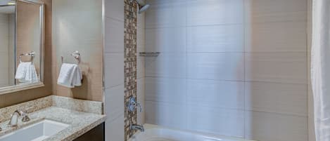A modern bathroom with a large bathtub, a sink, and a shower area.