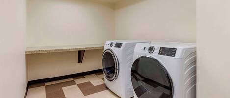 A laundry room with two front-loading washing machines, a bench, and a patterned floor.