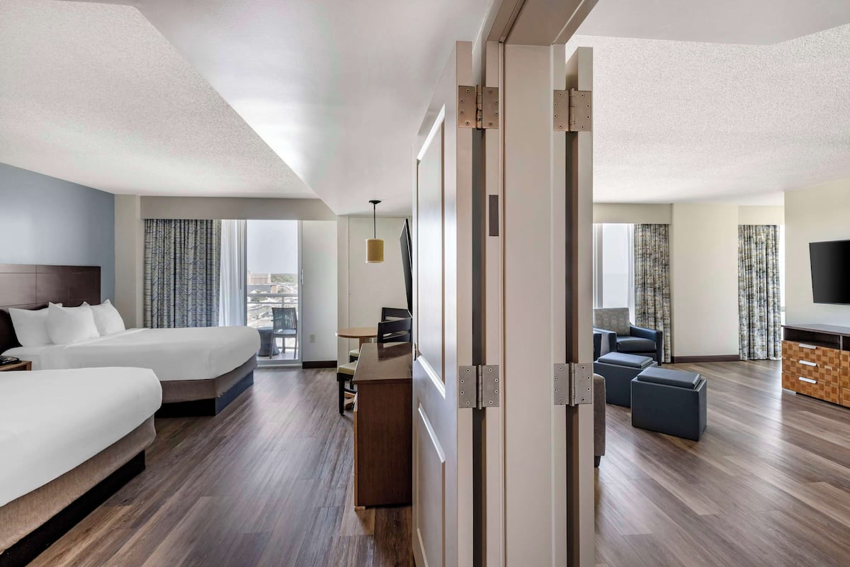 A hotel room with a large bed, a desk, a chair, and a TV.