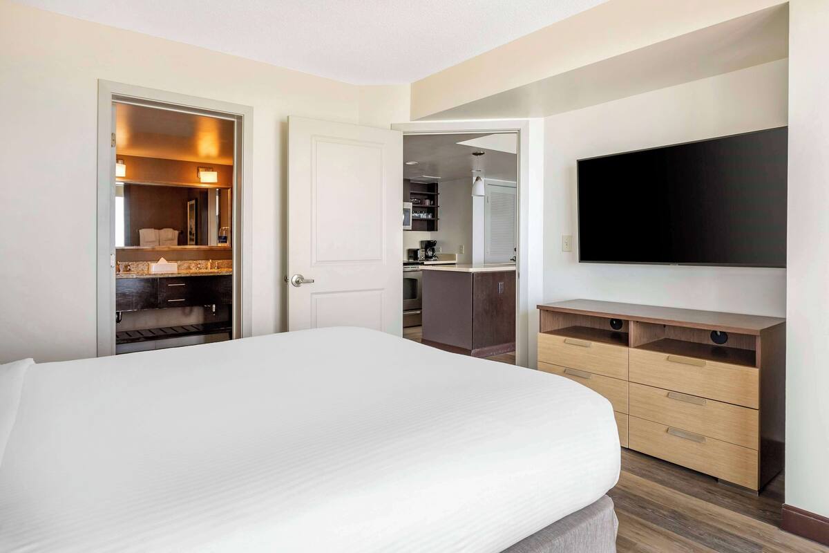 A hotel room with a bed, a TV, a wardrobe, and a small kitchenette.