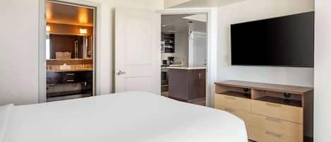A hotel room with a bed, a TV, a wardrobe, and a small kitchenette.