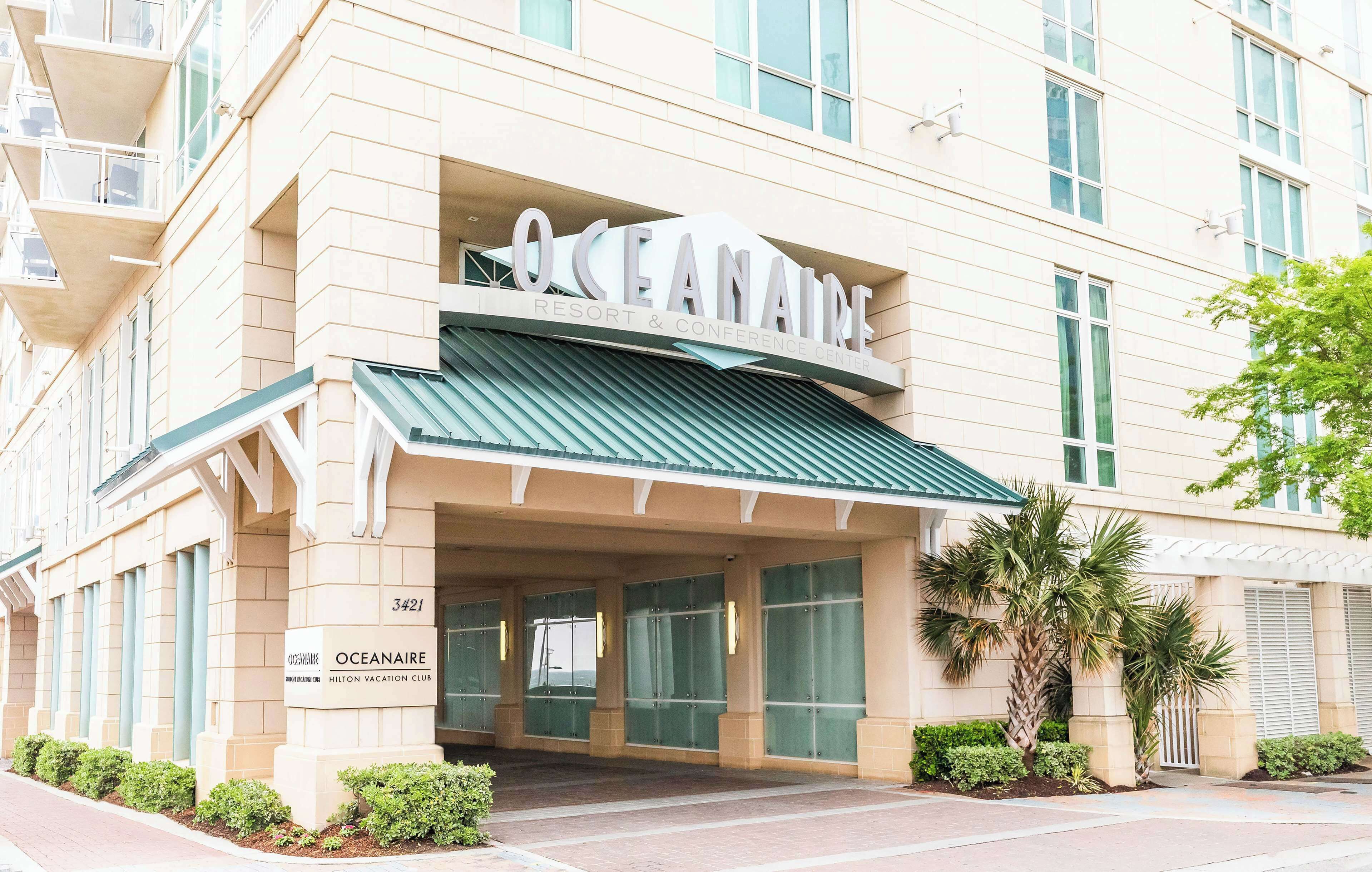 Das Außere des Oceanaire Resort & Conference Center, mit einem modernen architektonischen Design, einer markanten Eingangspartie, großen Fenstern und einem grünen Vordach.
