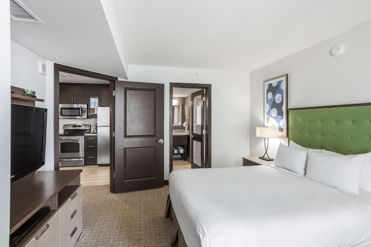 A hotel room with a bed, a TV, a microwave, and a kitchenette.
