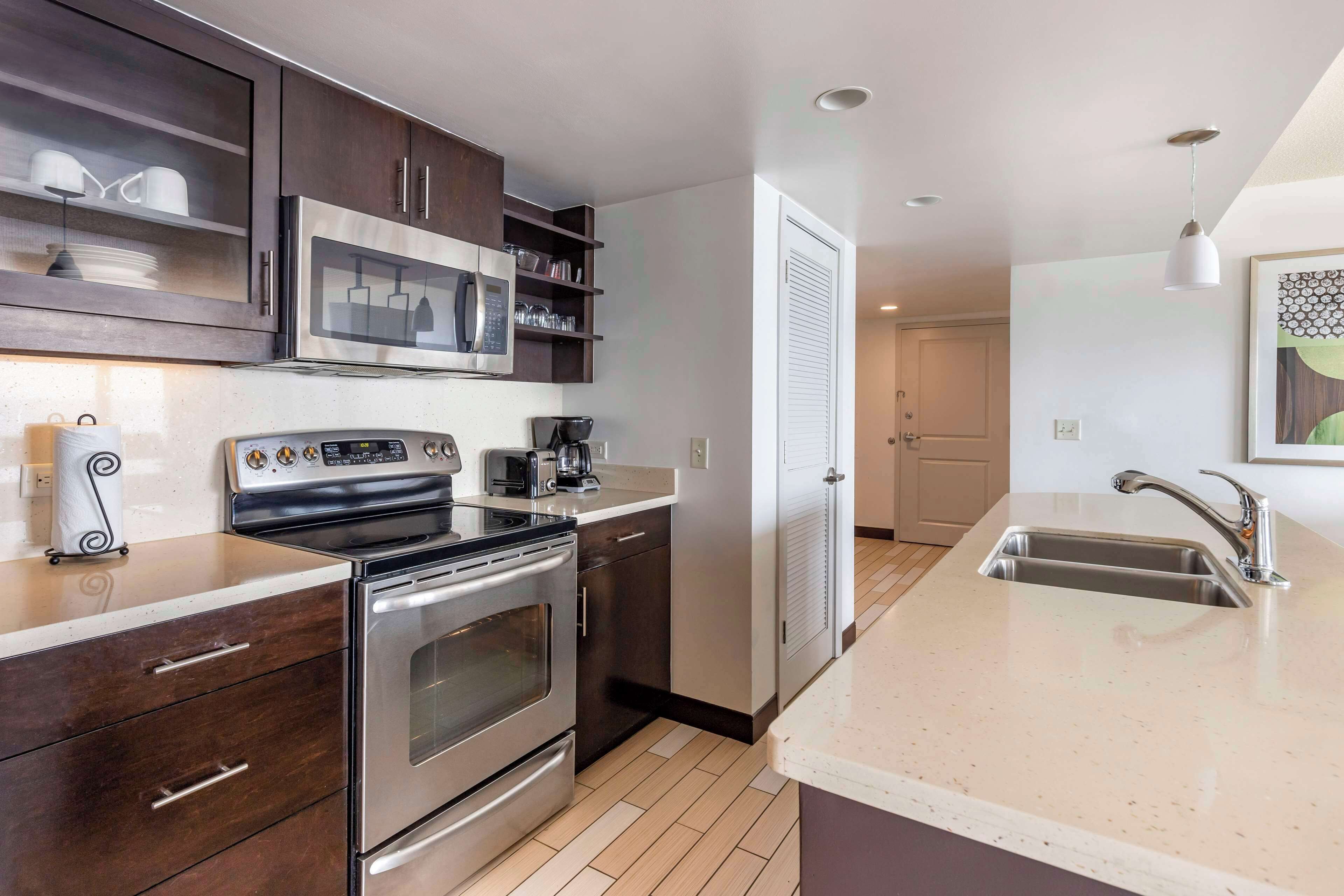 A modern kitchen with stainless steel appliances, dark wooden cabinets, and a large island with a sink.