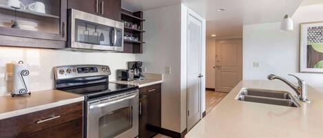 A modern kitchen with stainless steel appliances, dark wooden cabinets, and a large island with a sink.
