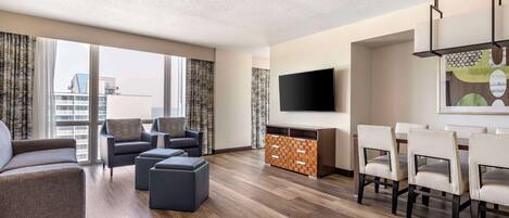 Una sala de estar moderna con un sofá, sillones, una mesa de centro, un televisor y un comedor con sillas.
