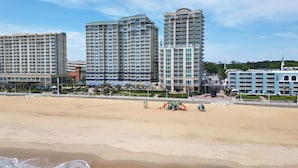Un hotel frente a la playa con varios edificios altos, una playa de arena y una zona de juegos.