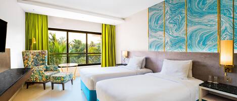 Habitación de hotel con dos camas, un escritorio, una silla y un ventanal con cortinas.
