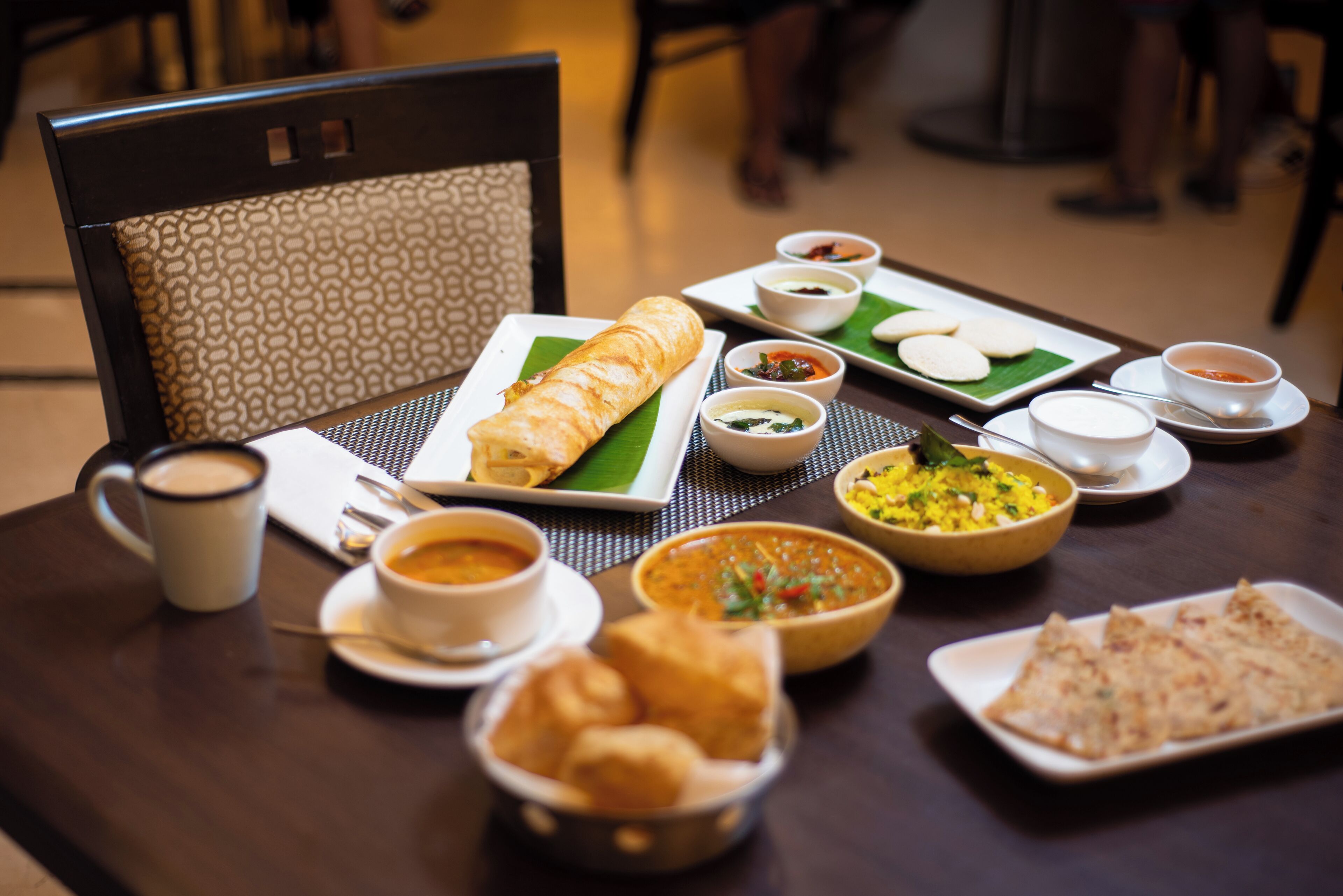A dining table with various dishes, including a rolled bread, bowls of soup, and a plate of triangular food items.