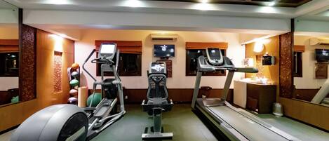 Un gimnasio con cintas de correr, elíptica y bicicleta estática.
