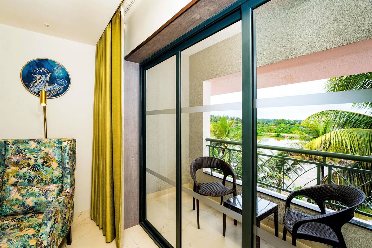 A balcony with two wicker chairs, a sofa, and a view of greenery.