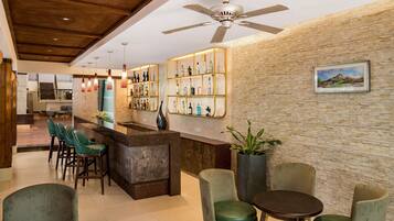 A hotel lobby with a reception desk, seating area, and a ceiling fan.