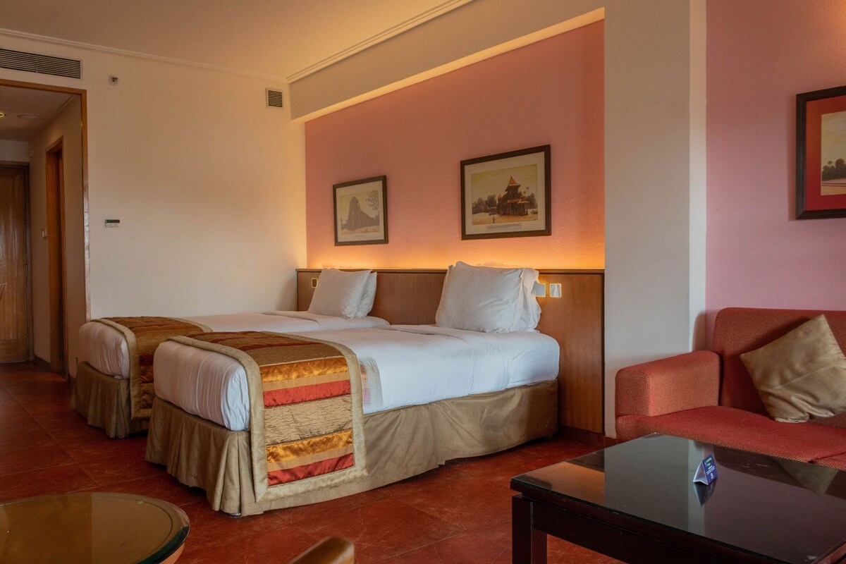 Une chambre d’hôtel comprenant un lit, deux tables de chevet, une chaise et une table en verre.