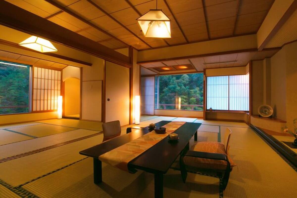 Une pièce de style japonais traditionnel, avec un sol recouvert de tatamis, une table basse et des portes coulissantes.