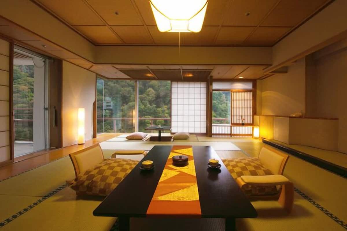 Um quarto tradicional japonês com tatames, uma mesa baixa, almofadas e portas corrediças.