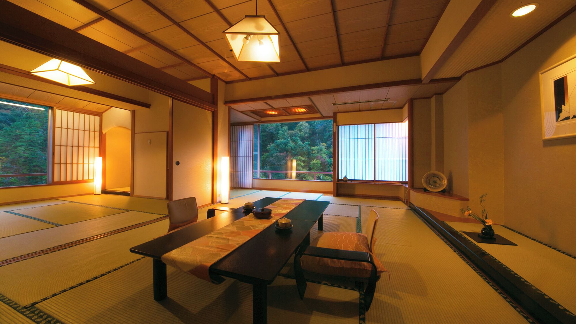 Une pièce de style japonais traditionnel, avec un sol recouvert de tatamis, une table basse, des chaises et des portes coulissantes.