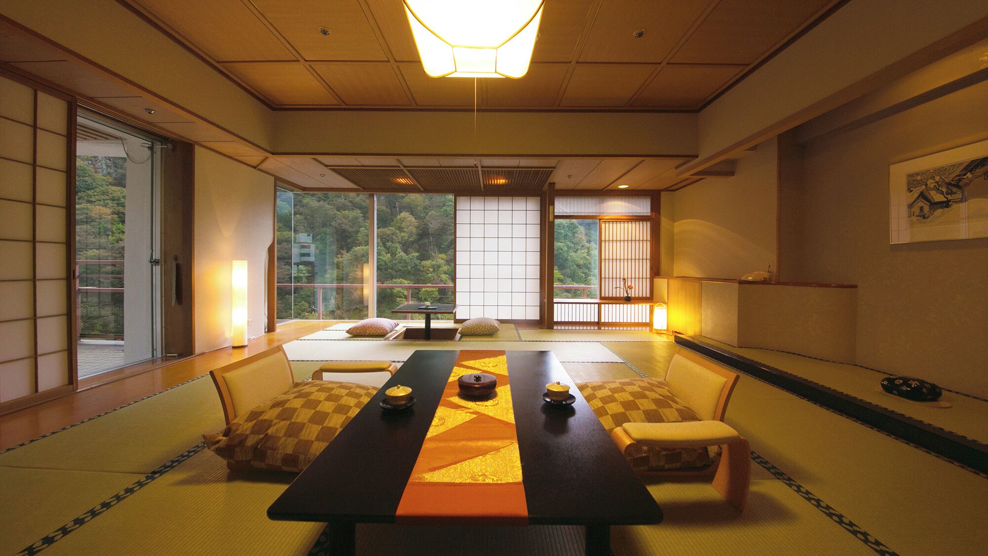 Une pièce de style japonais traditionnel, avec un sol recouvert de tatamis, une table basse avec des coussins, des portes coulissantes et une vue sur une zone boisée.