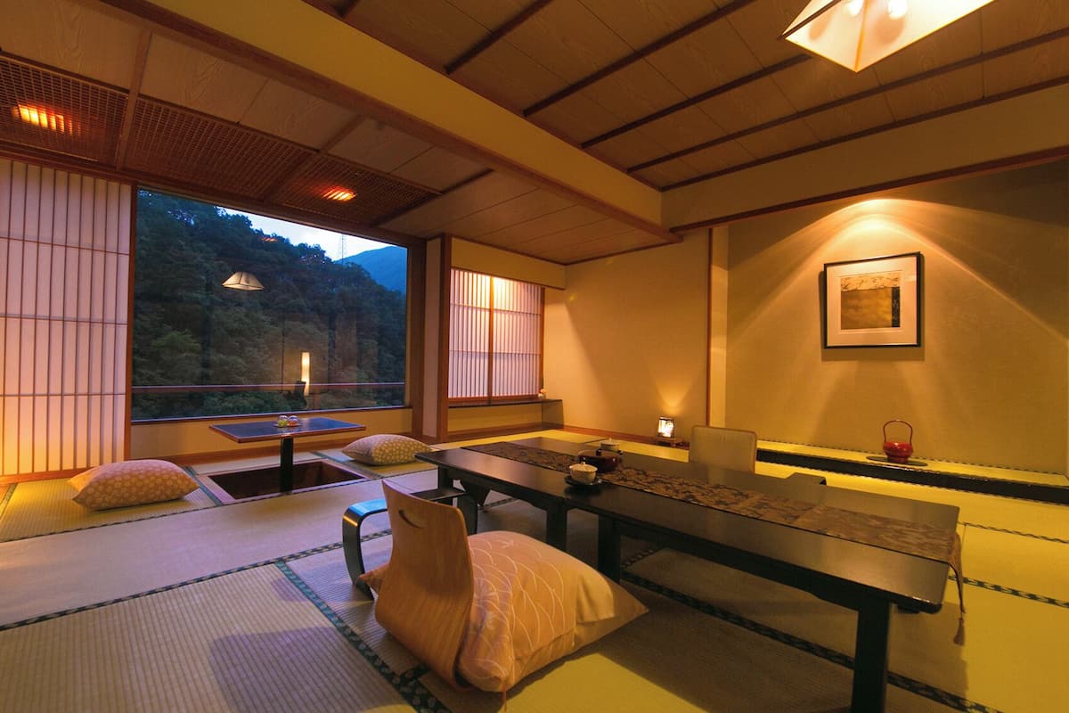 Une pièce de style japonais traditionnel, avec un sol recouvert de tatamis, une table basse, des coussins et des portes coulissantes.