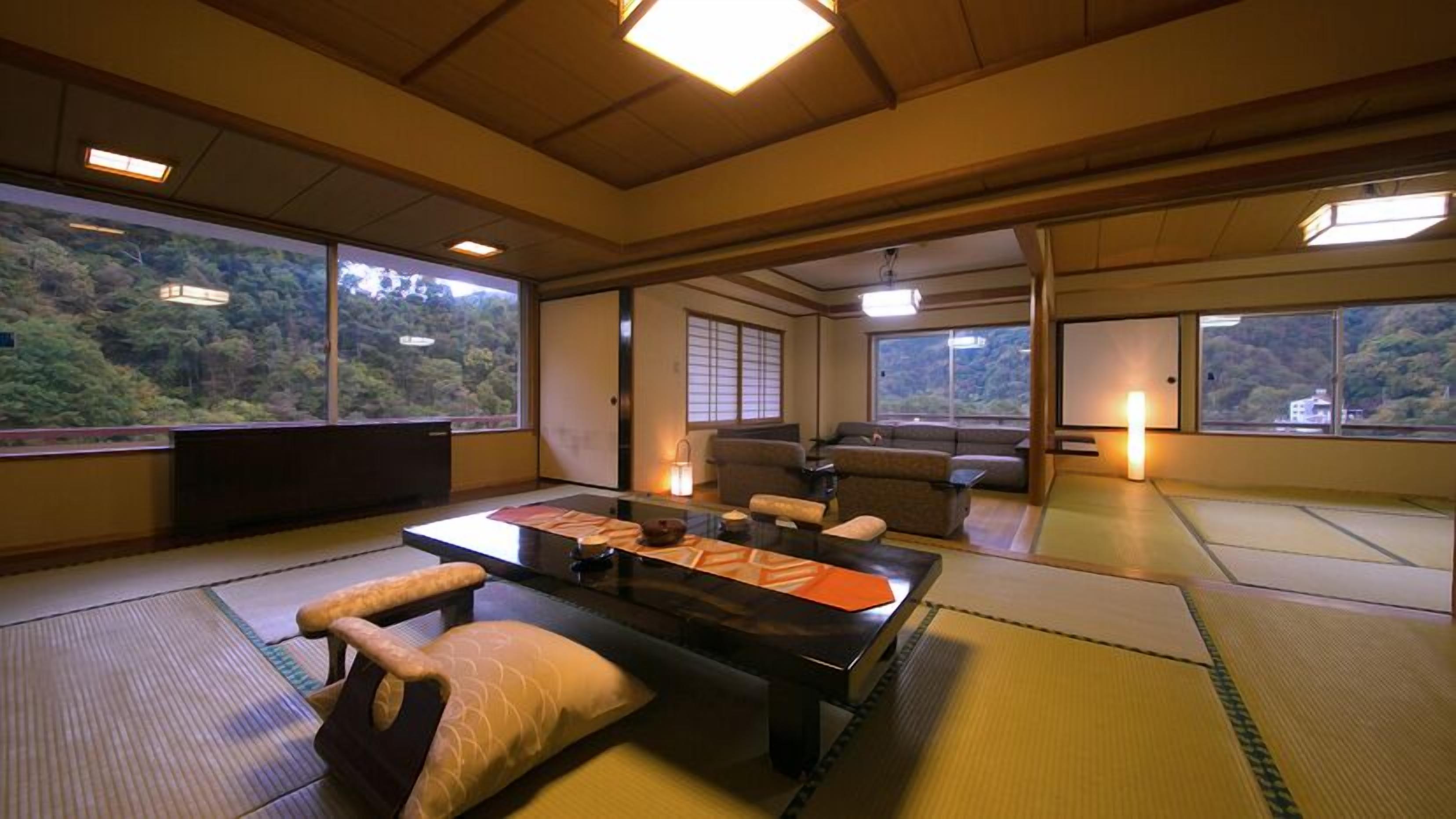 Une pièce de style japonais traditionnel, avec un sol recouvert de tatamis, une table basse, des coussins et un canapé.