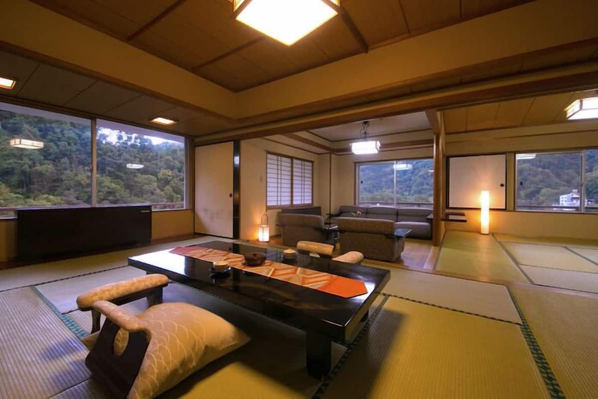 Um quarto japonês tradicional com tatames, uma mesa baixa, almofadas e um sofá.