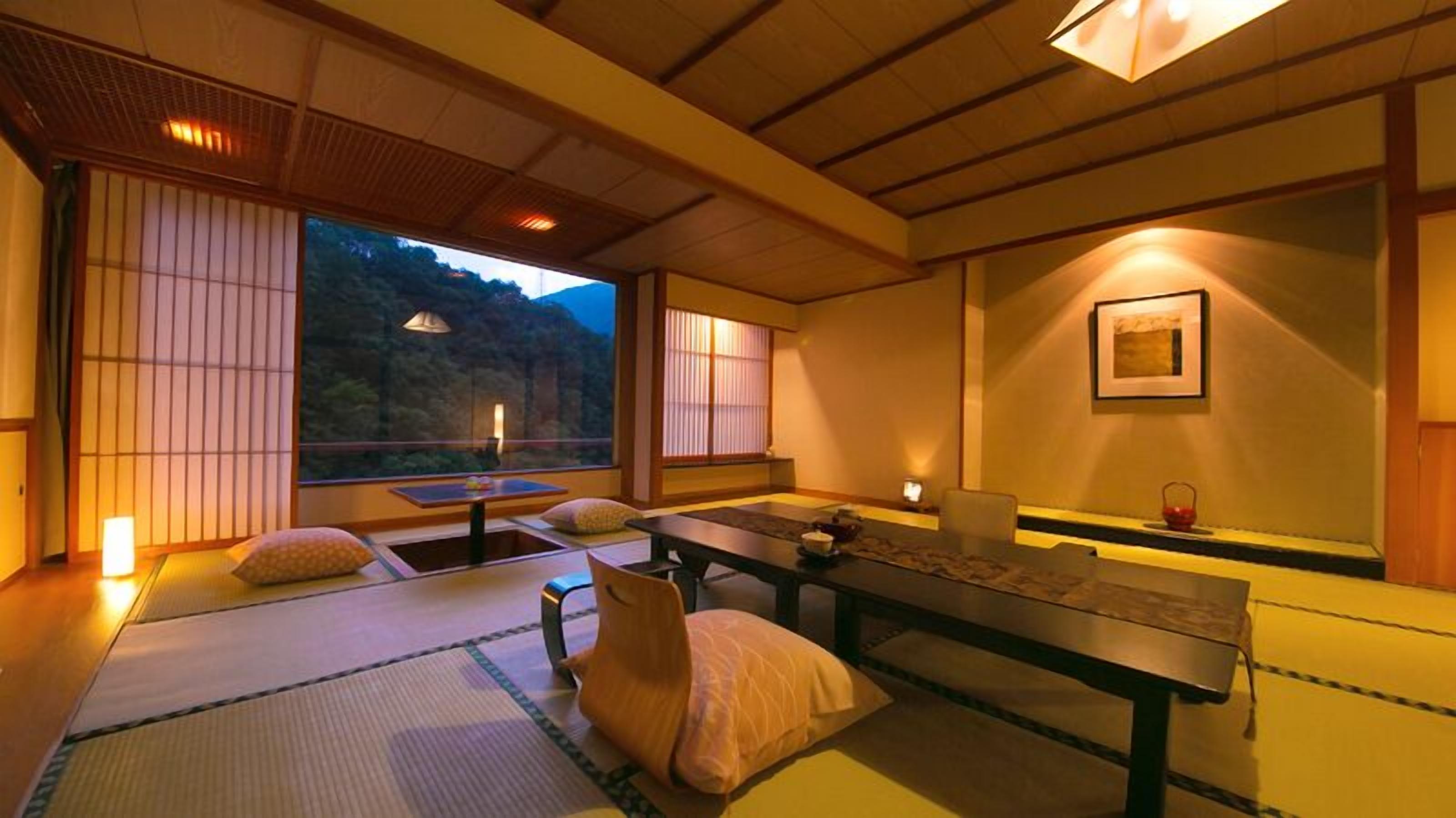Une pièce de style japonais traditionnel, avec un sol recouvert de tatamis, une table basse, des coussins et des portes coulissantes.