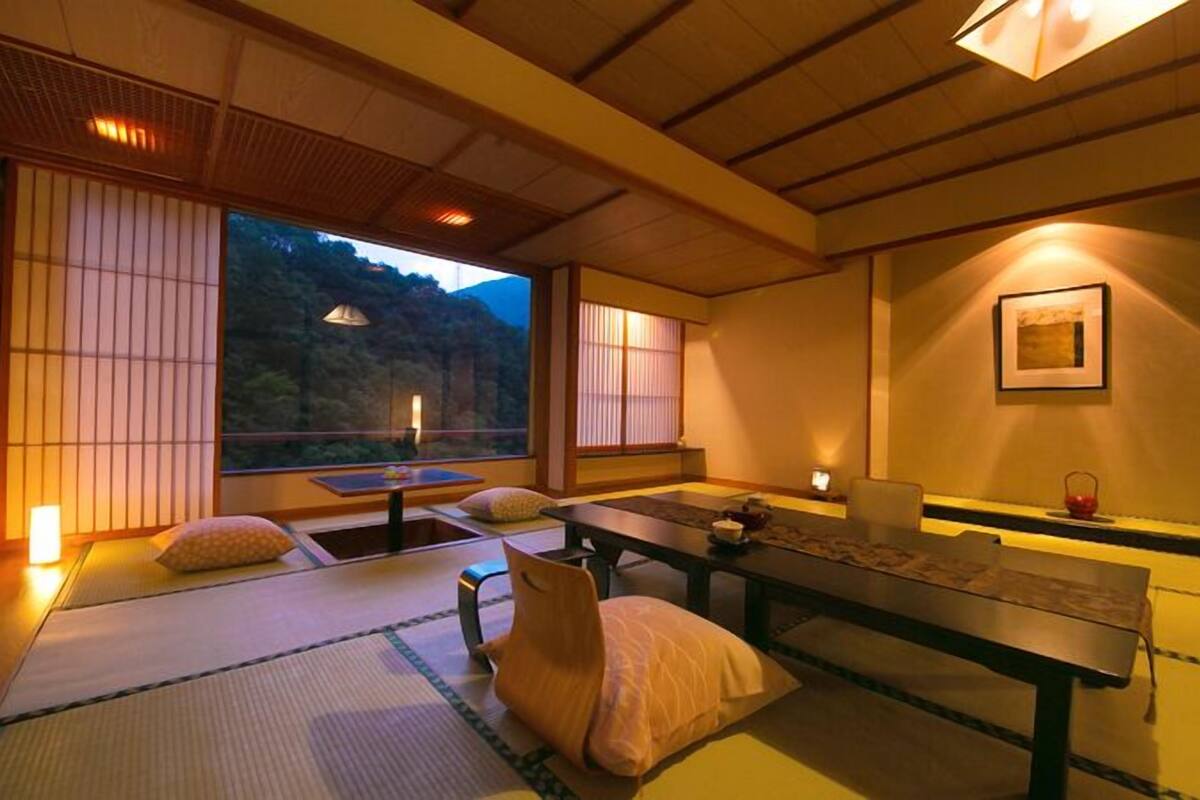 Une pièce de style japonais traditionnel, avec un sol recouvert de tatamis, une table basse, des coussins et des portes coulissantes.