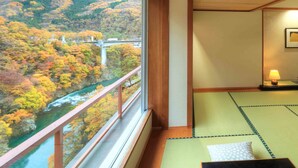 Habitación con esteras de tatami, vista a un río y un puente, y techo de madera.