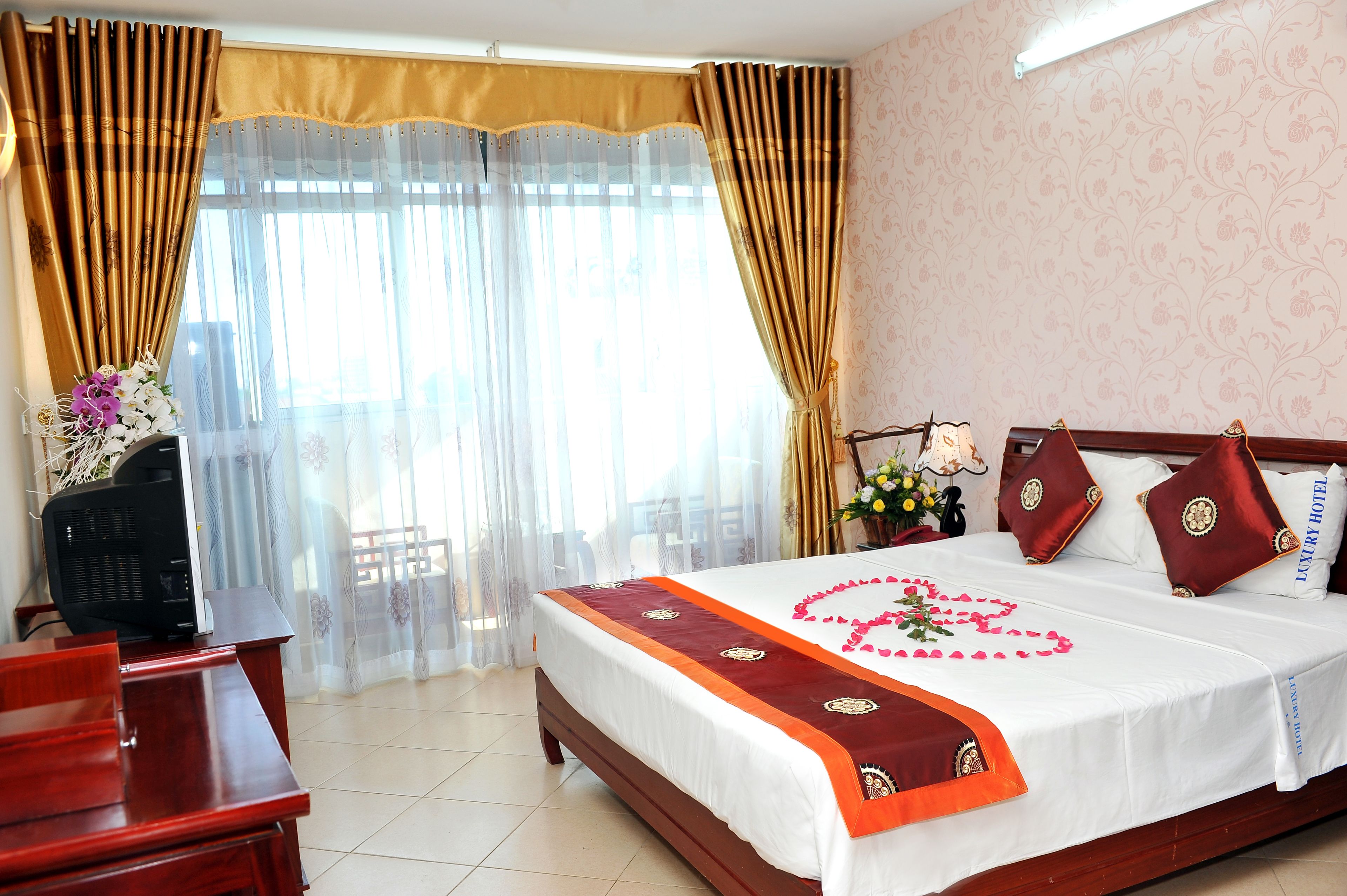 A hotel room with a large bed, a desk, and a TV.