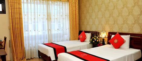A hotel room with two beds, each with a red and white bedspread, a wooden headboard, and a nightstand with a lamp.