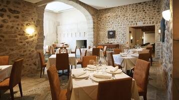 A restaurant with stone walls, white tables, and brown chairs.