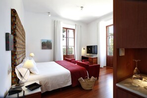 A hotel room with a bed, a desk with a TV, a lamp, a chair, and a window. - Sa Cabana Hotel Rural & Spa - Adults Only (Consell)