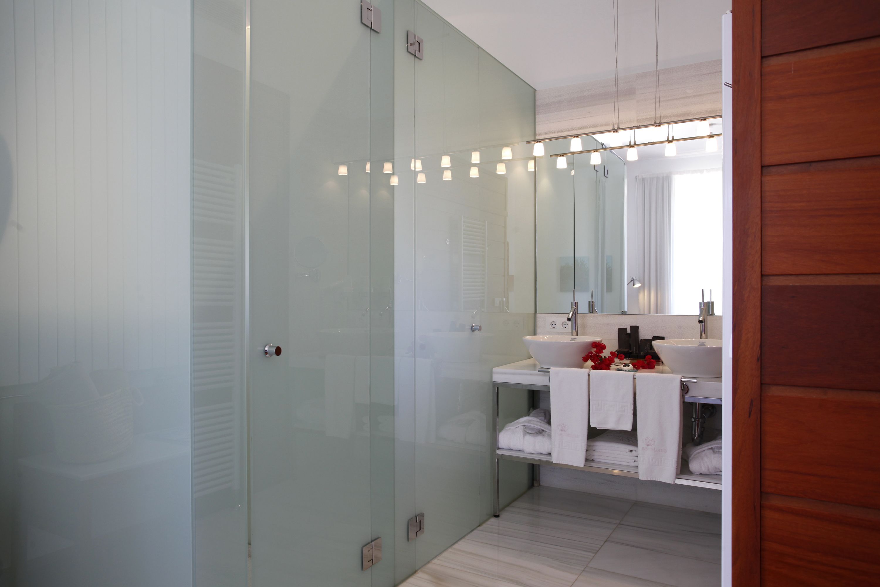 A modern bathroom with a glass shower enclosure, a white sink, and a mirror above the sink.