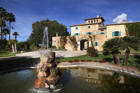 A stone building with a fountain in the foreground, surrounded by greenery and a clear sky. - Sa Cabana Hotel Rural & Spa - Adults Only (Consell)