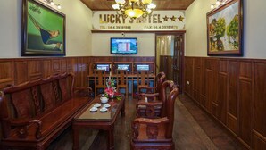 A traditional hotel lobby with wooden paneling, a reception desk, and a television displaying a menu. - Lucky 3 Hotel & Travel  (Hanoi)