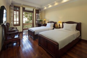 Habitación de hotel con dos camas, muebles de madera, un televisor y un balcón con vistas.
