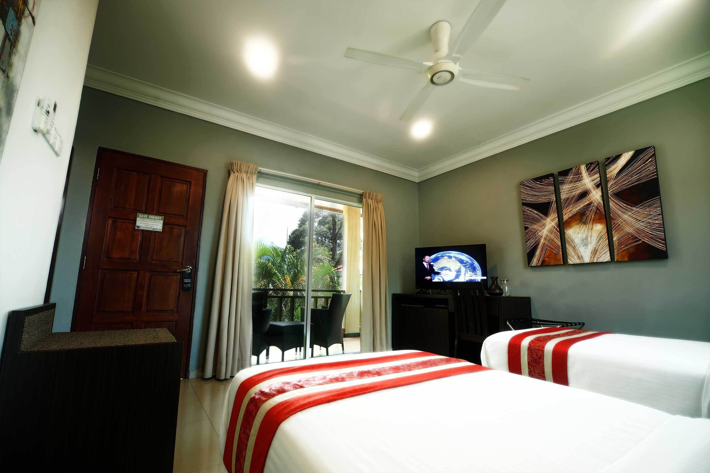 A hotel room with two beds, a television, a ceiling fan, and a window with curtains.