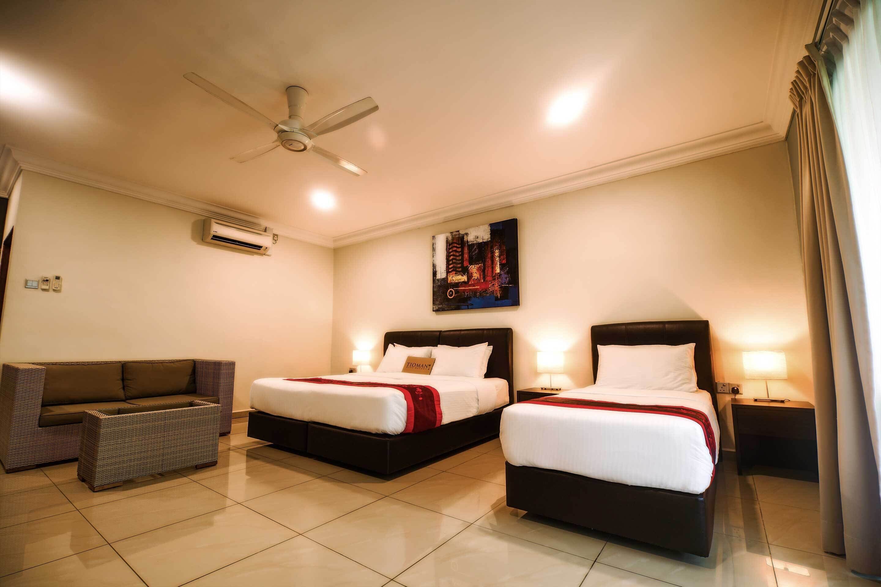 A hotel room with two beds, a sofa, a ceiling fan, and an air conditioning unit.