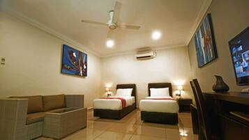 A hotel room with two beds, a sofa, a TV, and a ceiling fan.