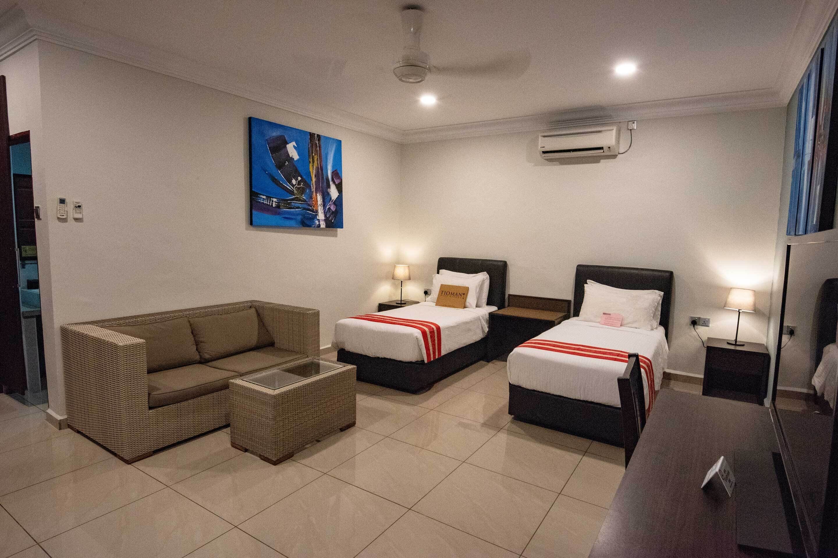 Habitación de hotel con dos camas, un sofá, una mesita y un televisor.